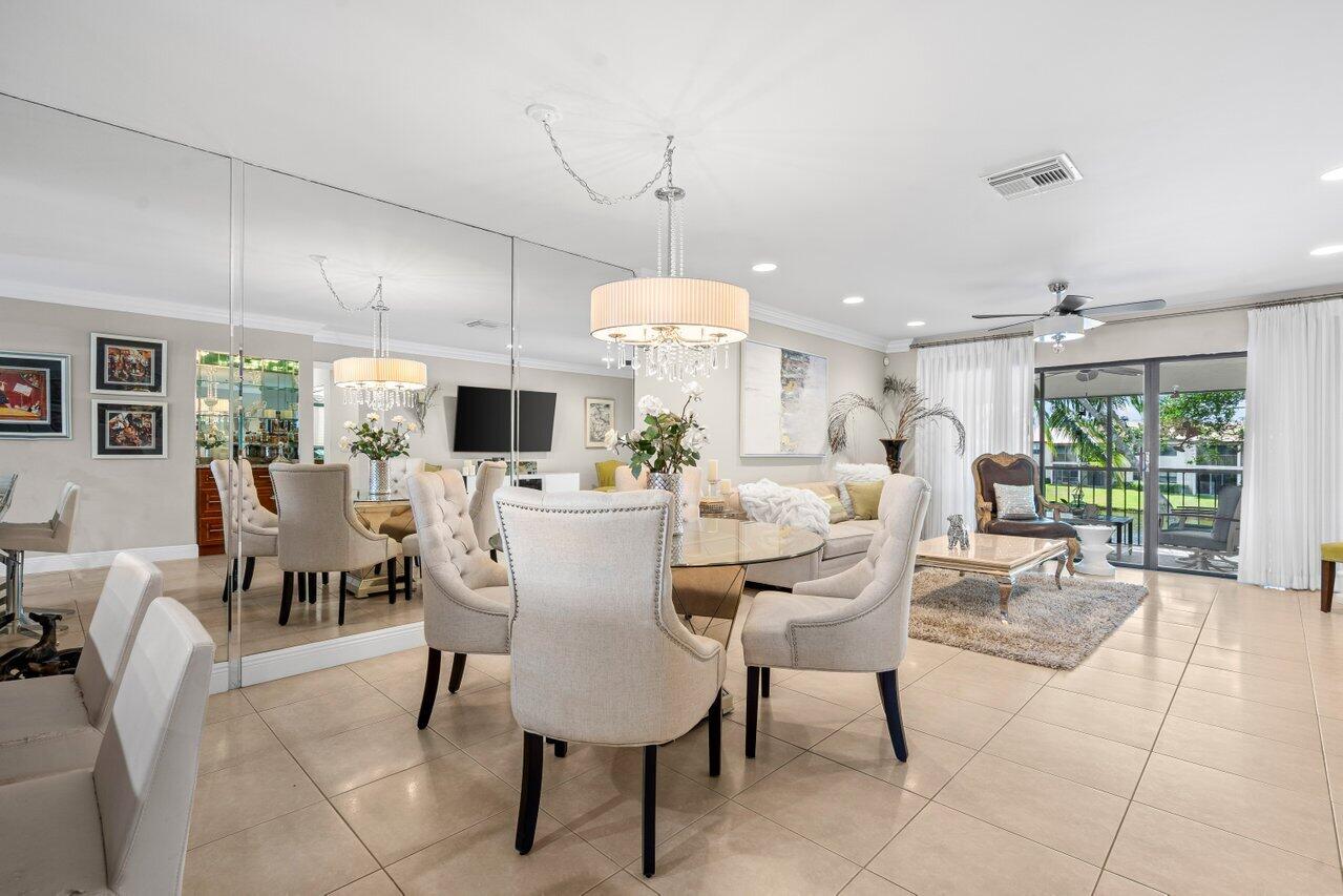 9261 Vista Del Lago, Unit H Boca Raton, FL 33428 - Photo 7 of 27 a dining room with furniture a chandelier and a flat screen tv