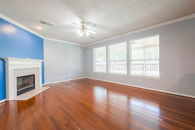 a view of an empty room with wooden floor fireplace and a window