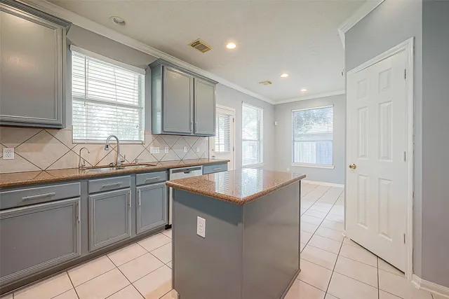 a kitchen with granite countertop a sink and white cabinets
