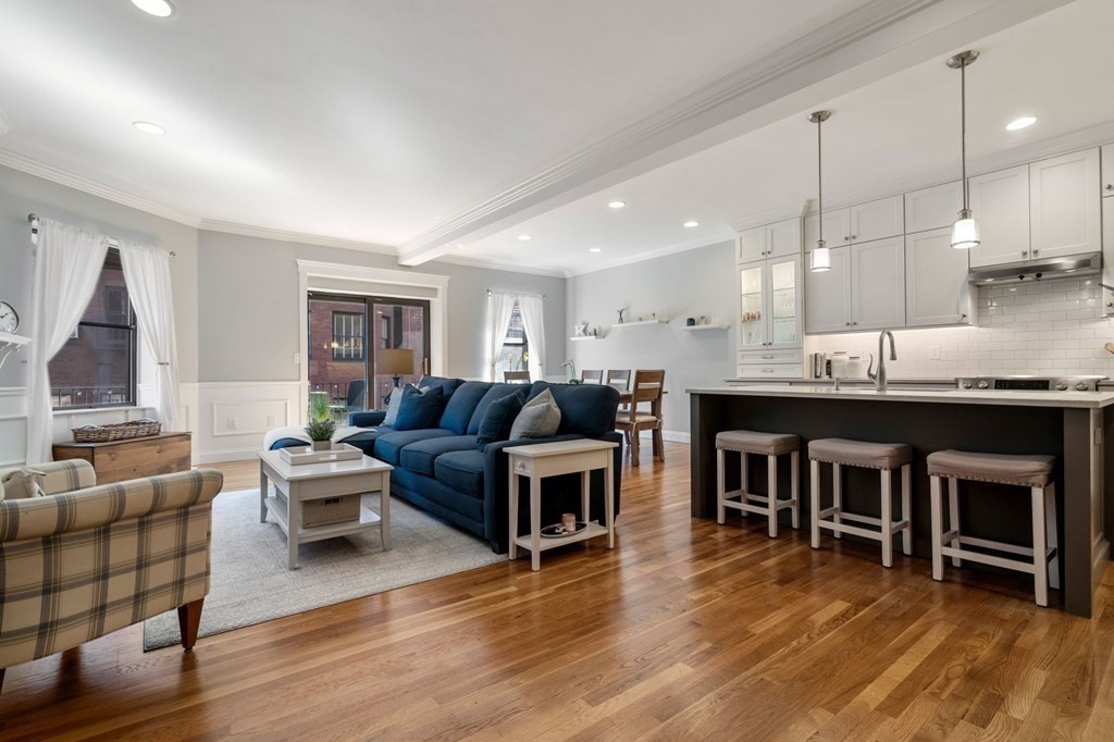 a living room with furniture a wooden floor and a kitchen