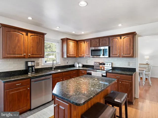 a kitchen with granite countertop kitchen island granite countertop stainless steel appliances a sink a counter top space cabinets and a window