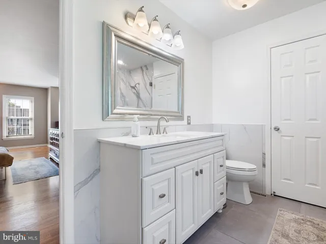 a spacious bathroom with a double vanity sink a toilet and a mirror
