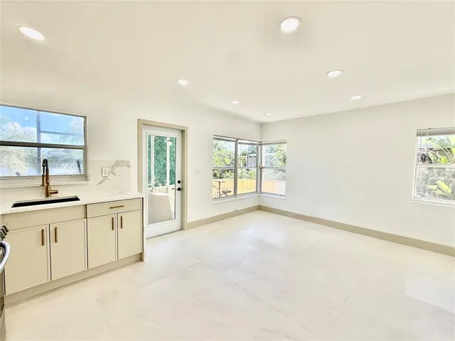 a large white kitchen with granite countertop a sink and dishwasher with a large window
