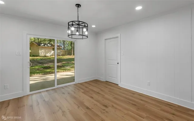 an empty room with wooden floor exposed radiator and windows