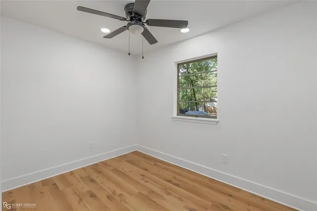 an empty room with a window and a ceiling fan