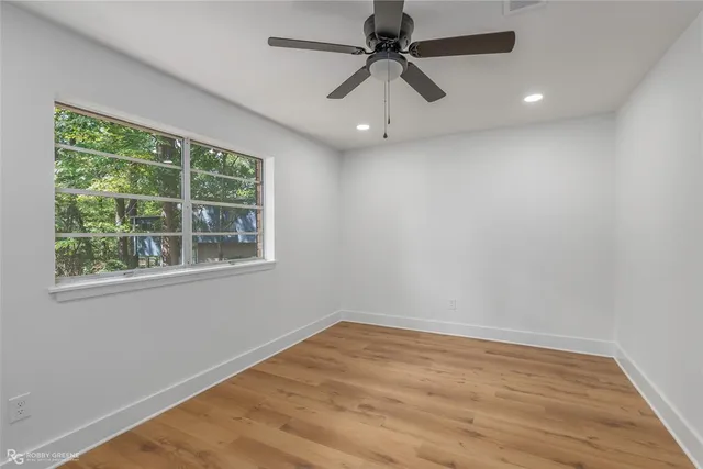 an empty room with a window and a fan