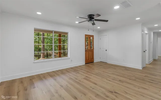 a view of an empty room with a window and wooden floor