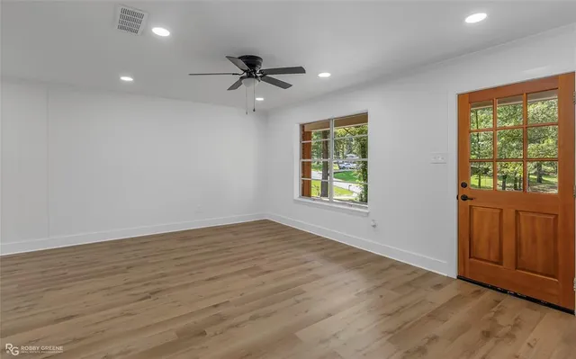 an empty room with wooden floor cabinet and windows