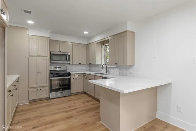 a kitchen with kitchen island granite countertop a sink cabinets and stainless steel appliances