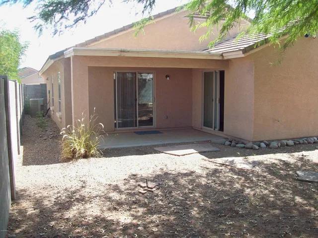 a backyard of a house with large trees and a wooden fence