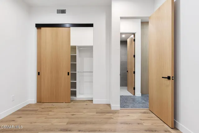 a view of a hallway with wooden floor and closet