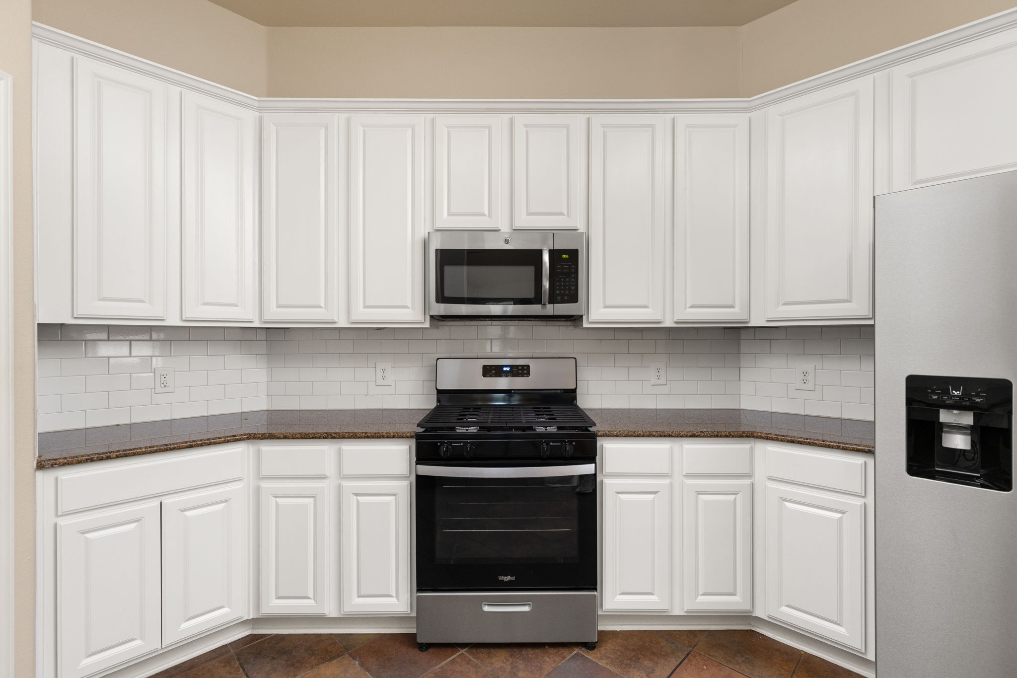 784 Sampson Kyle, TX 78640 - Photo 20 of 40 Gleaming stone countertops and crisp cabinetry frame the modern stainless steel appliances in this kitchen.