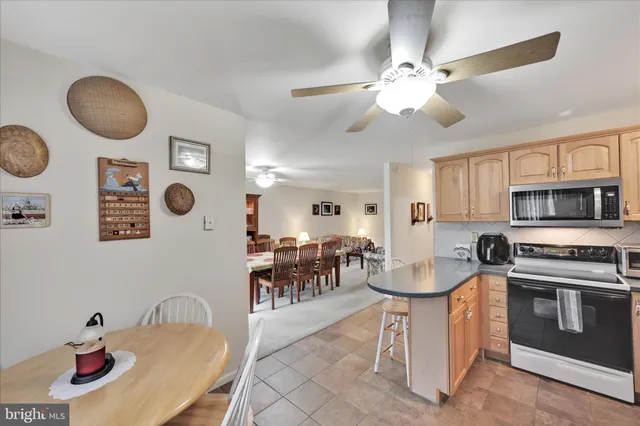 a kitchen with stainless steel appliances granite countertop a stove top oven a sink a dining table and chairs with wooden floor