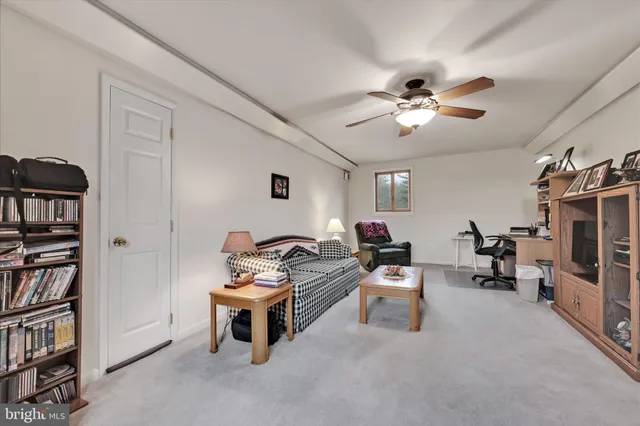 a living room with furniture a ceiling fan and a book shelf