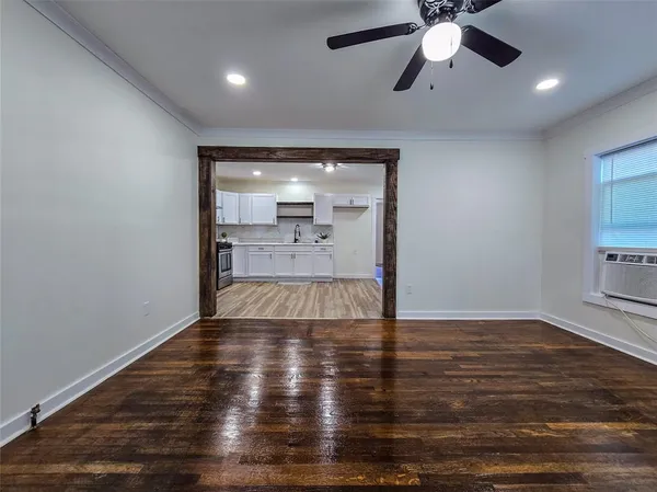 an empty room with wooden floor chandelier fan and windows