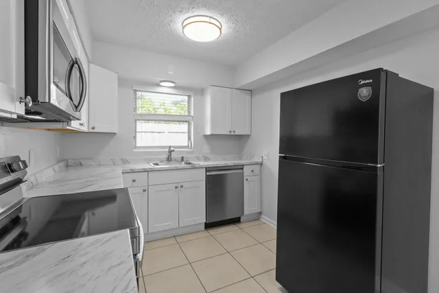 a kitchen with a refrigerator sink and cabinets