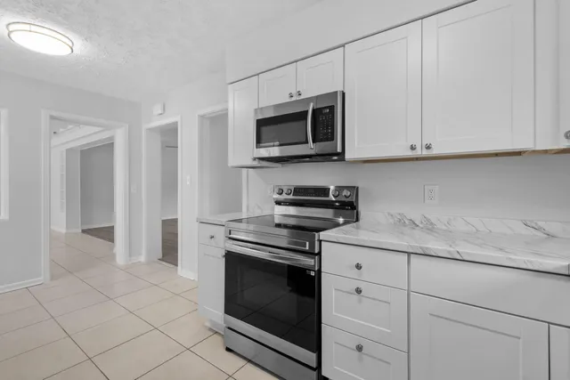 a kitchen with stainless steel appliances granite countertop white cabinets and a stove top oven