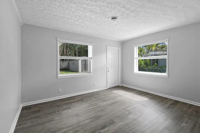 an empty room with wooden floor and windows