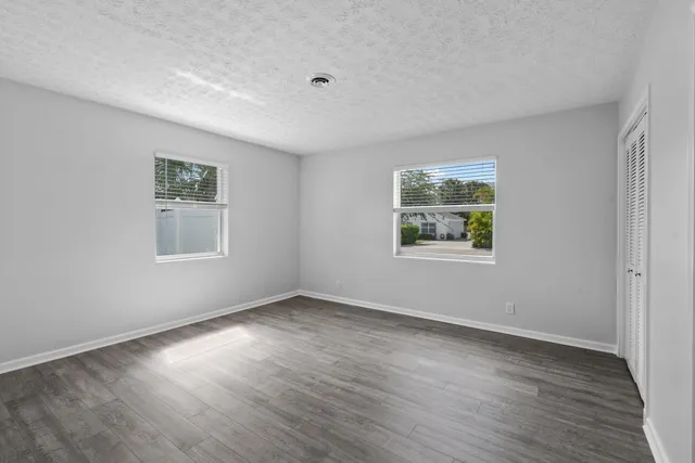 a view of a big room with wooden floor and windows