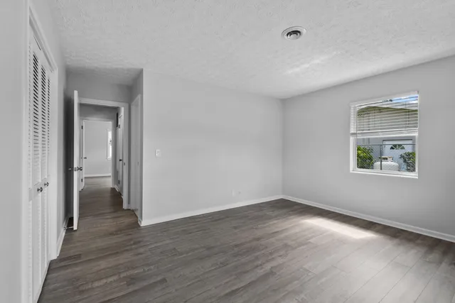 a view of an empty room with closet and a window