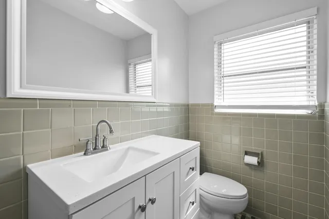 a bathroom with a toilet sink vanity and mirror
