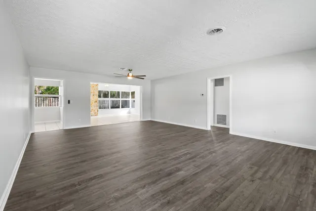 a view of an empty room with wooden floor and windows