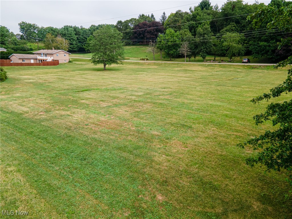 View of grassy yard with view of wooded area
