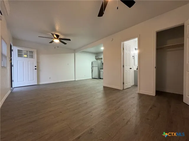 a view of a livingroom with a ceiling fan wooden floor and window