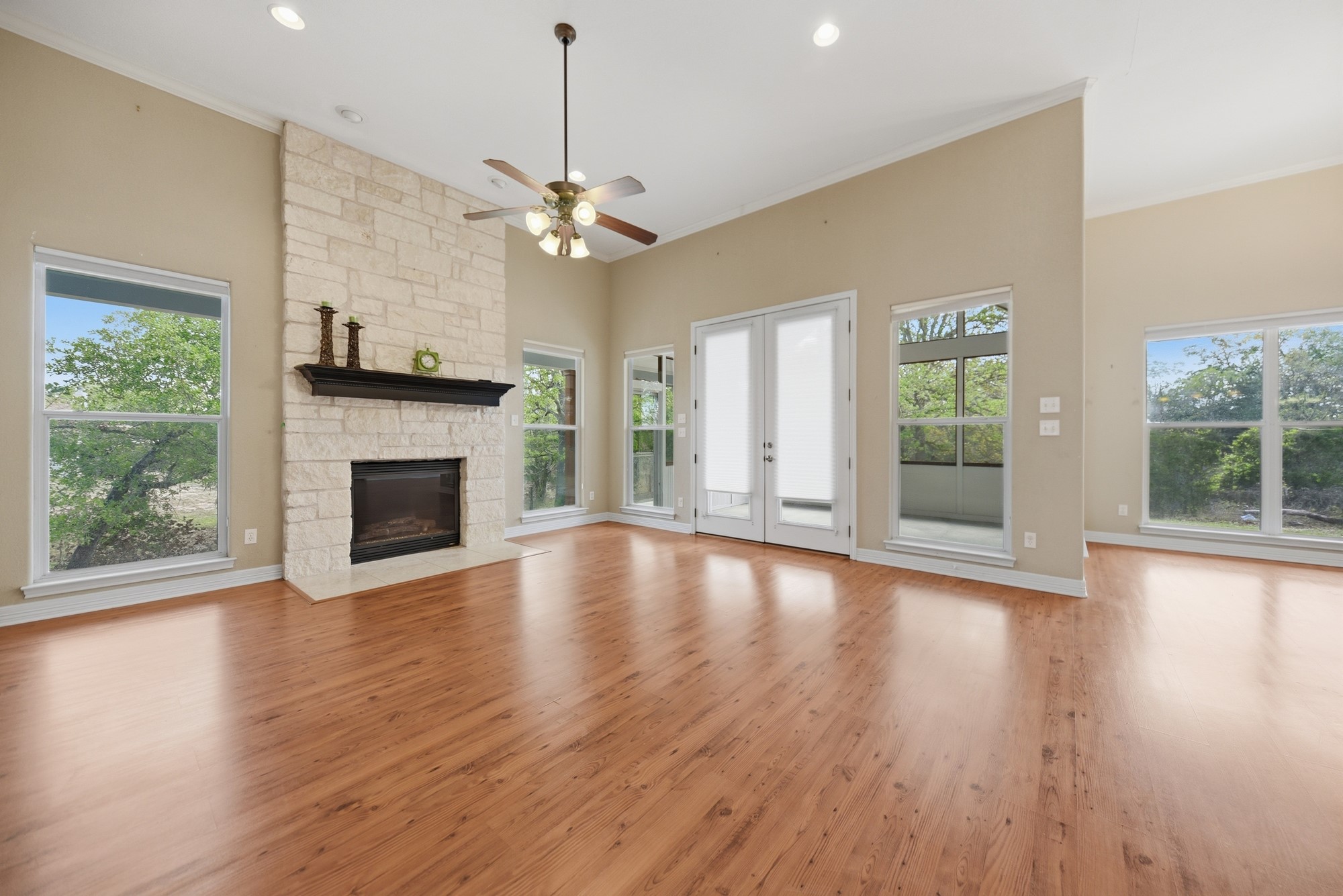 350 Owl Creek Road Giddings, TX 78942 - Photo 7 of 29 Unfurnished living room with a ceiling fan, recessed lighting, light wood-type flooring, french doors, and a stone fireplace