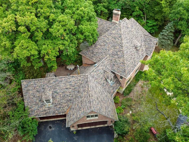 an aerial view of a house with a yard and large trees