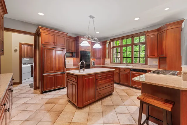 a kitchen with stainless steel appliances granite countertop a stove a sink a refrigerator and chairs