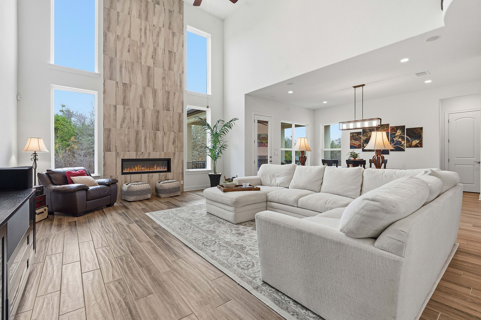 2824 Wedgescale Pass Leander, TX 78641 - Photo 4 of 40 Living area featuring a tiled fireplace, wood tiled floors, a ceiling fan, and a high ceiling