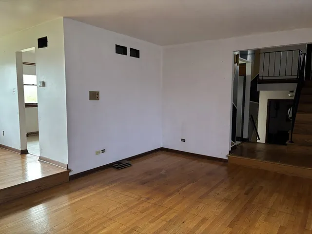 a view of an empty room with wooden floor and a fireplace
