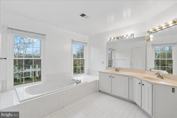 a large white bathroom with a large tub sink vanity and granite