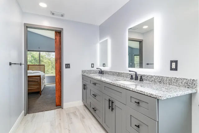a en suite bathroom with a granite countertop sink and a mirror