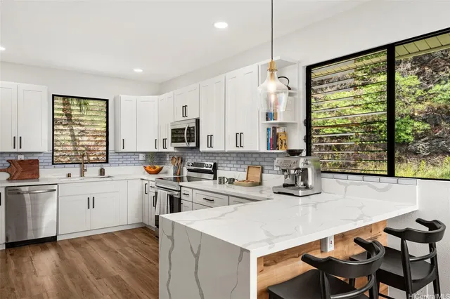 a kitchen with a stove a sink a kitchen island with a dining table and chairs