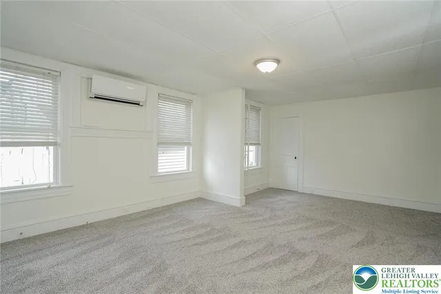 a view of an empty room with wooden floor and window