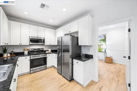 a kitchen with stainless steel appliances kitchen island granite countertop a dining table chairs and granite counter tops