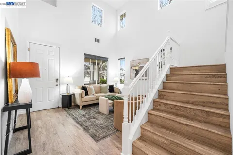 a living room with stainless steel appliances a dining table wooden floor and a kitchen view