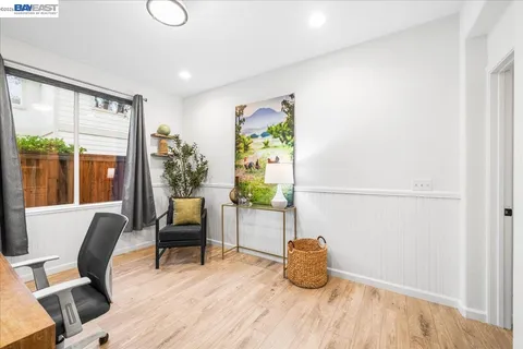 a living room with stainless steel appliances furniture a large window and a refrigerator