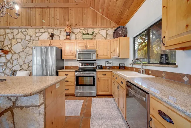 a kitchen with stainless steel appliances a table chairs refrigerator and cabinets