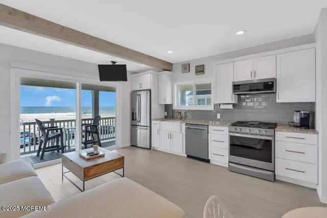 a living room with stainless steel appliances kitchen island granite countertop a stove and a refrigerator