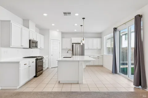 a large kitchen with stainless steel appliances lots of counter space and windows