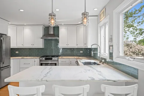 a kitchen with granite countertop a sink stainless steel appliances and white cabinets