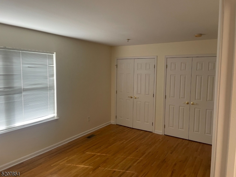 1527 Lamberts Mill Road, Unit 1A Westfield, NJ 07090 - Photo 13 of 13 a view of an empty room with wooden floor and a window