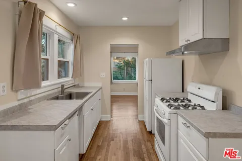 a kitchen with granite countertop a sink stove and refrigerator