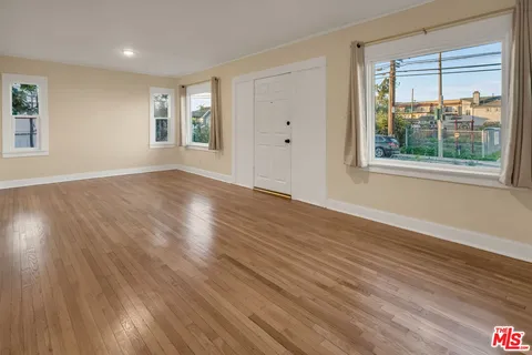 a view of empty room with wooden floor and fan