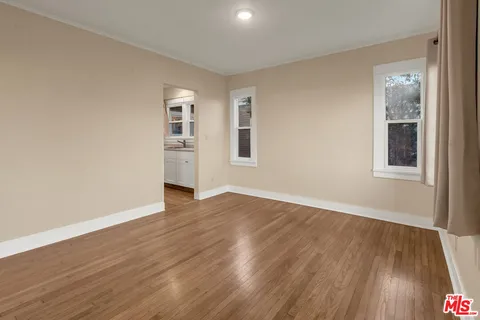 a view of an empty room with wooden floor and a window