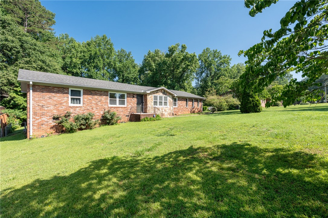 200 Echo Circle Easley, SC 29642 - Photo 32 of 35 A well-maintained brick residence is nestled amongst mature trees, featuring a generous front yard with natural shade.