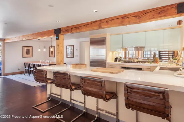 a dining hall with stainless steel appliances kitchen island granite countertop a dining table and chairs